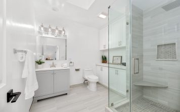 Modern white bathroom with glass shower, a cabinetry, and stylish lighting fixtures. Modern white bathroom with glass shower, a cabinetry, and stylish lighting fixtures.